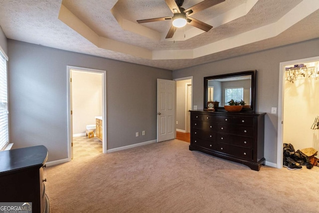 carpeted bedroom featuring connected bathroom, baseboards, a raised ceiling, and a textured ceiling