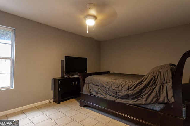 bedroom featuring light tile patterned floors, ceiling fan, multiple windows, and baseboards