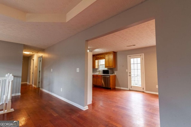 kitchen featuring a textured ceiling, stainless steel appliances, wood finished floors, and baseboards