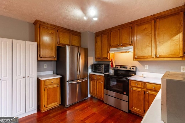 kitchen with light countertops, appliances with stainless steel finishes, brown cabinets, and under cabinet range hood