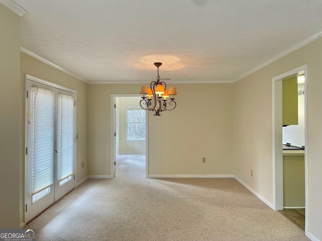 spare room with crown molding, a healthy amount of sunlight, and an inviting chandelier