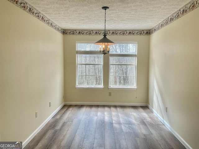 unfurnished dining area with hardwood / wood-style flooring, a chandelier, and a textured ceiling