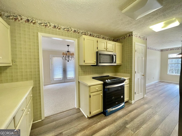 kitchen featuring hanging light fixtures, black electric range, a textured ceiling, and light wood-type flooring