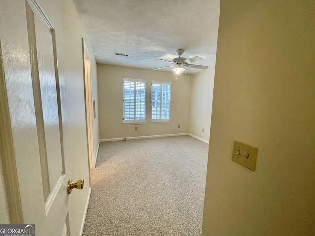 carpeted empty room with ceiling fan and a textured ceiling