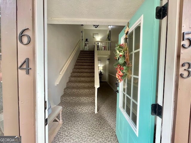 stairway featuring a textured ceiling