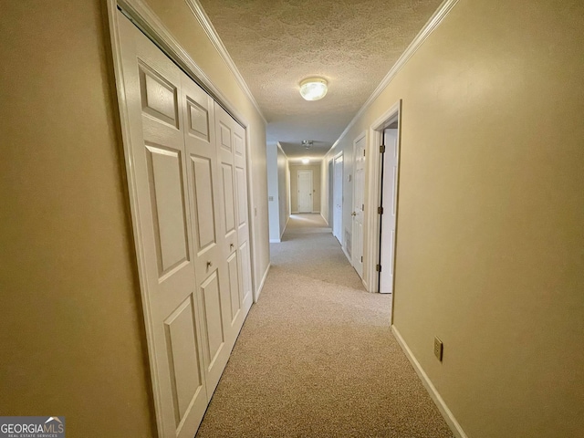 hallway with light carpet, ornamental molding, and a textured ceiling