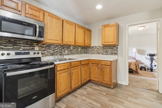 kitchen with tasteful backsplash, appliances with stainless steel finishes, light hardwood / wood-style floors, and sink