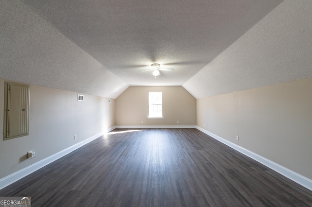 bonus room with lofted ceiling, a textured ceiling, dark hardwood / wood-style floors, and ceiling fan