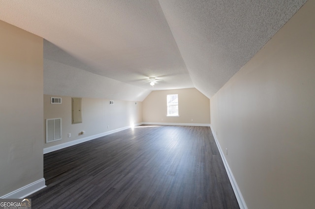 additional living space with lofted ceiling, dark hardwood / wood-style floors, and a textured ceiling