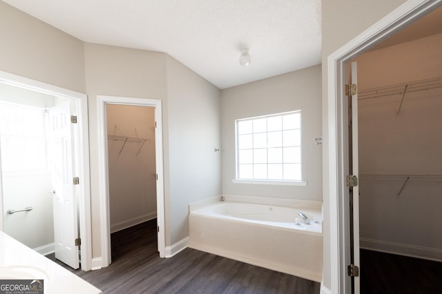 bathroom featuring wood-type flooring, a textured ceiling, and a tub