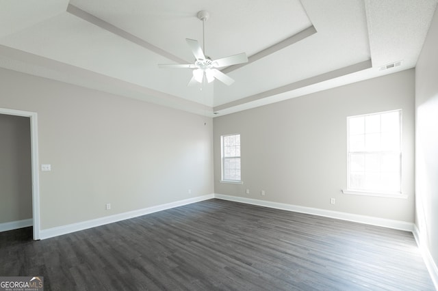 empty room with ceiling fan, dark hardwood / wood-style flooring, and a raised ceiling