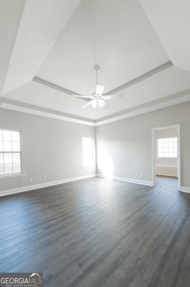 empty room featuring a raised ceiling, a textured ceiling, and ceiling fan