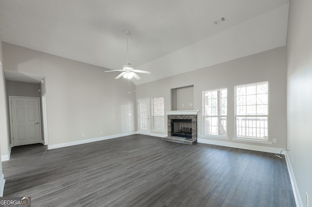 unfurnished living room featuring ceiling fan, lofted ceiling, a stone fireplace, and dark hardwood / wood-style flooring