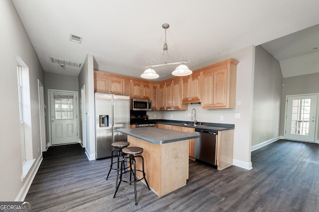 kitchen featuring a kitchen island, appliances with stainless steel finishes, pendant lighting, dark hardwood / wood-style flooring, and light brown cabinets