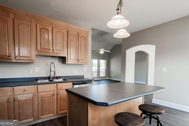 kitchen featuring pendant lighting, sink, dark hardwood / wood-style floors, a center island, and stainless steel dishwasher