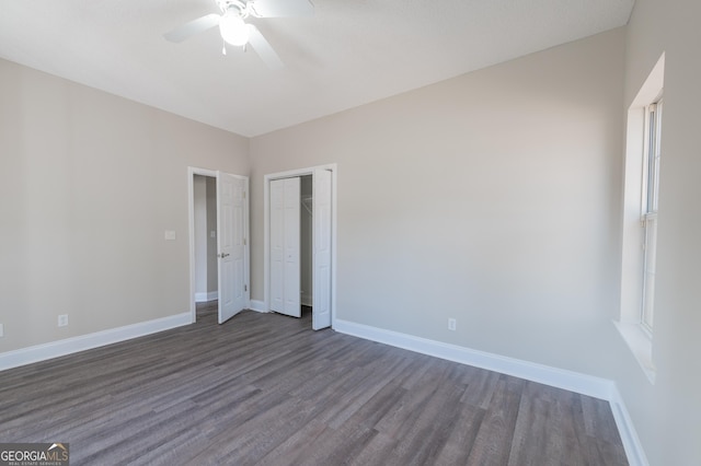 unfurnished bedroom featuring dark wood-type flooring, ceiling fan, multiple windows, and a closet