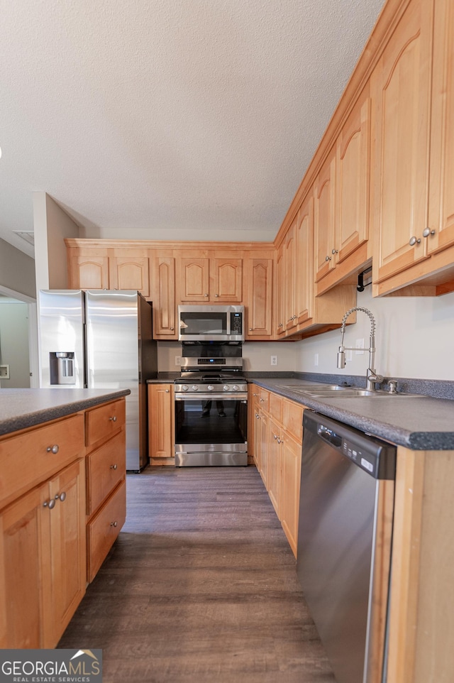 kitchen featuring light brown cabinetry, sink, a textured ceiling, appliances with stainless steel finishes, and dark hardwood / wood-style flooring