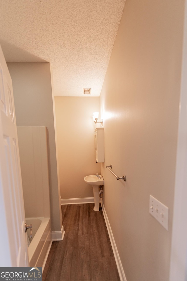 bathroom featuring wood-type flooring, a washtub, and a textured ceiling