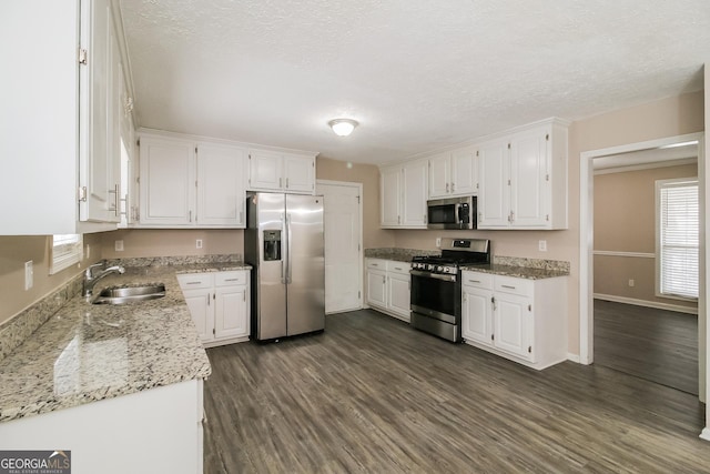 kitchen with white cabinetry, appliances with stainless steel finishes, sink, and light stone counters