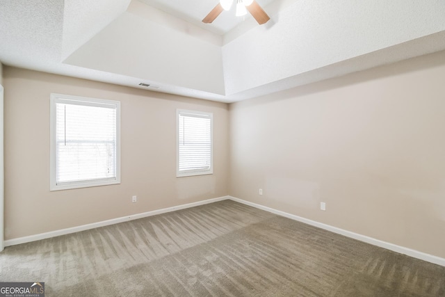 carpeted empty room featuring ceiling fan, a tray ceiling, and a textured ceiling