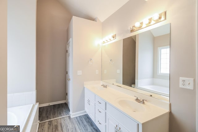 bathroom with lofted ceiling, toilet, vanity, hardwood / wood-style flooring, and tiled bath