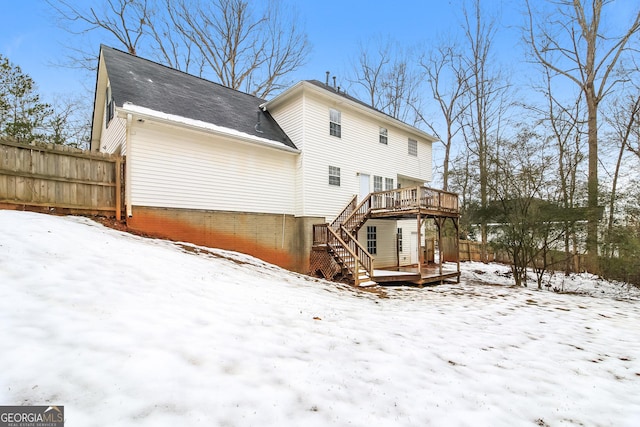 snow covered back of property featuring a wooden deck