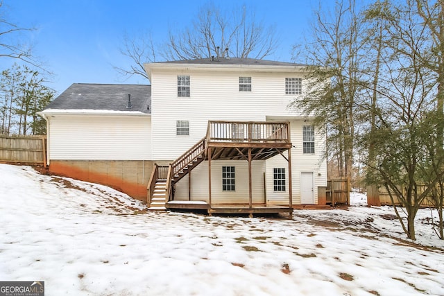 snow covered back of property with a deck