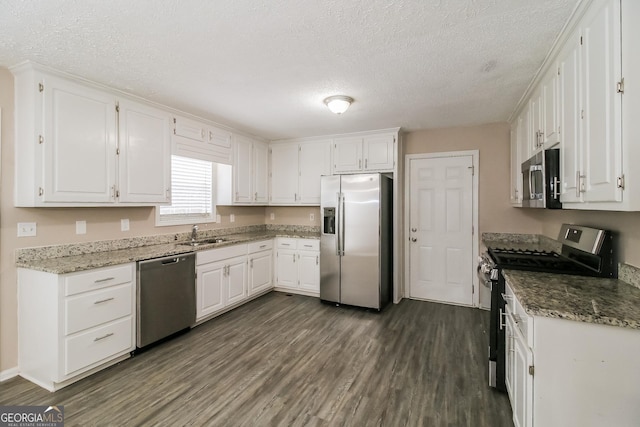 kitchen with stainless steel appliances, a textured ceiling, and white cabinets