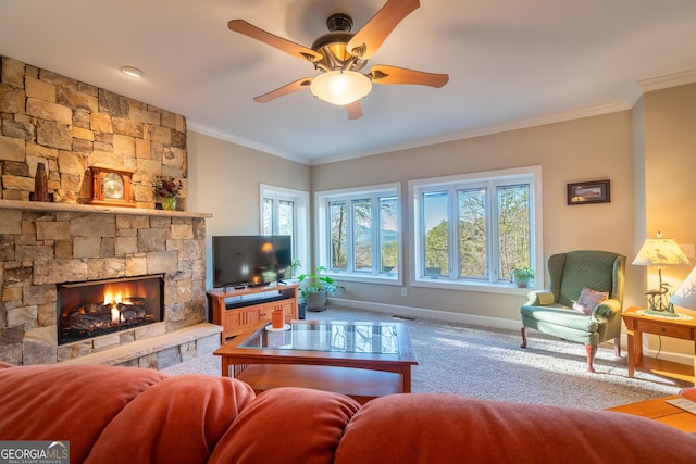 living room featuring crown molding, a stone fireplace, ceiling fan, and carpet