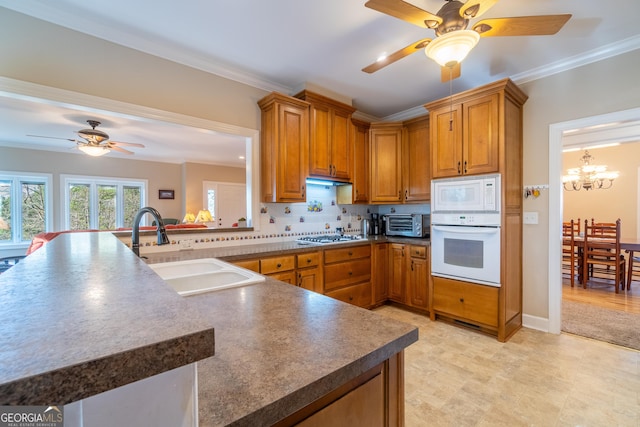 kitchen with sink, white appliances, tasteful backsplash, ornamental molding, and kitchen peninsula