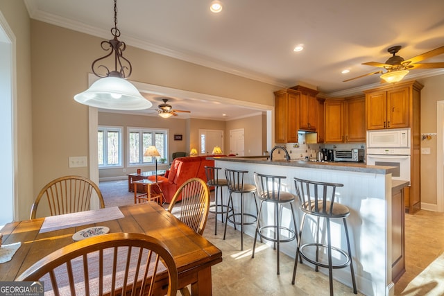 kitchen with ornamental molding, pendant lighting, white appliances, and kitchen peninsula