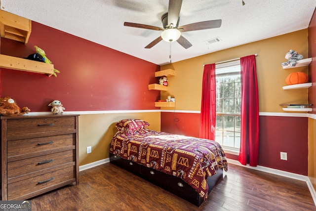 bedroom with ceiling fan, a textured ceiling, and dark hardwood / wood-style flooring