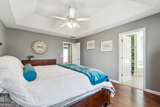 bedroom featuring a raised ceiling, dark hardwood / wood-style floors, and ceiling fan