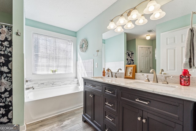 bathroom featuring vanity, hardwood / wood-style floors, a textured ceiling, and a bathtub