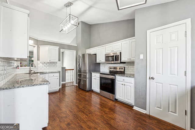 kitchen with vaulted ceiling, pendant lighting, white cabinets, light stone counters, and stainless steel appliances