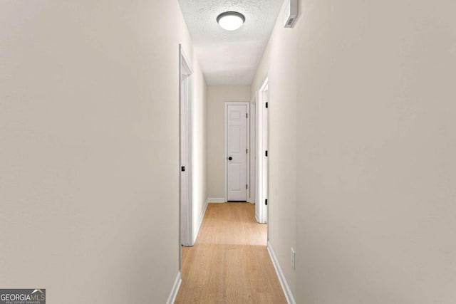 hall with a textured ceiling and light hardwood / wood-style floors