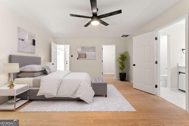 bedroom featuring connected bathroom, a textured ceiling, light hardwood / wood-style flooring, and ceiling fan