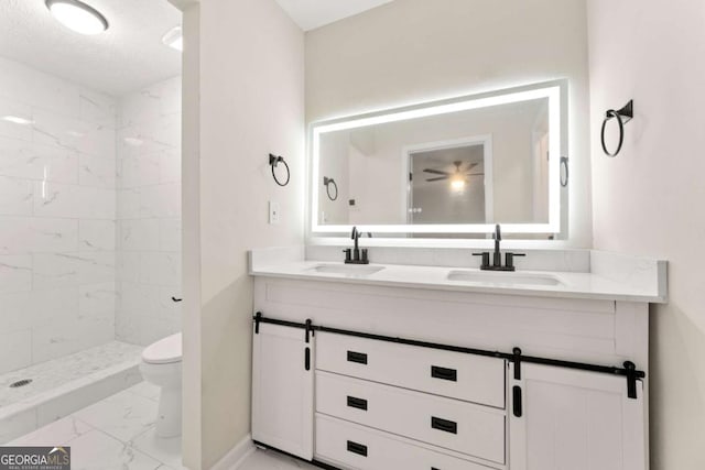 bathroom featuring tiled shower, vanity, toilet, and a textured ceiling