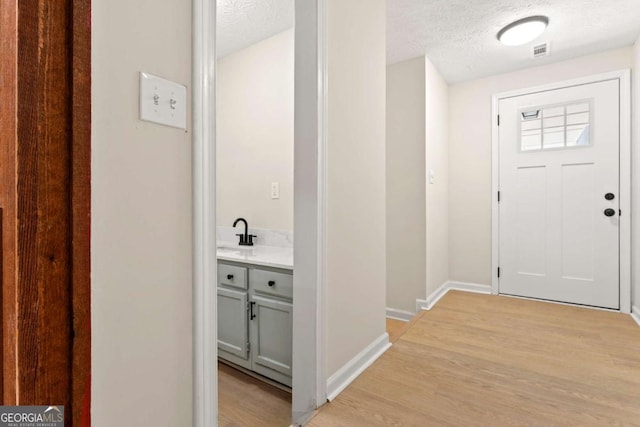 entrance foyer with sink, light hardwood / wood-style floors, and a textured ceiling