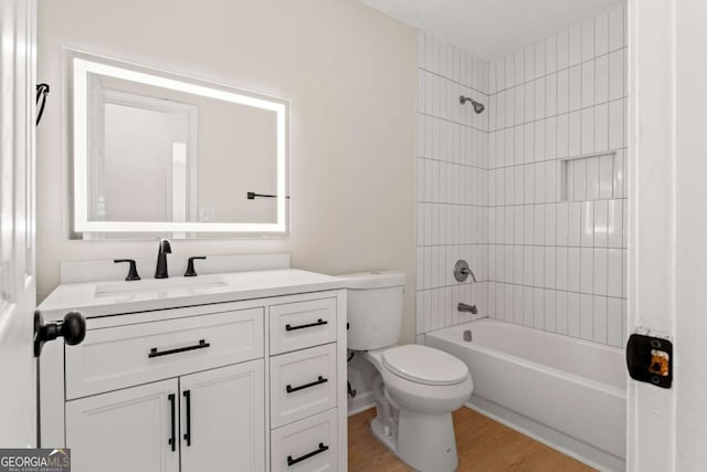 full bathroom featuring vanity, tiled shower / bath combo, wood-type flooring, and toilet