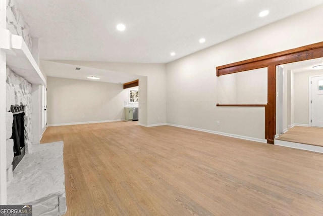 unfurnished living room with a high end fireplace, light hardwood / wood-style floors, and vaulted ceiling