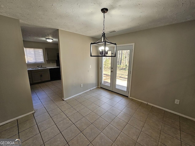 unfurnished dining area featuring light tile patterned flooring, sink, a notable chandelier, and a healthy amount of sunlight