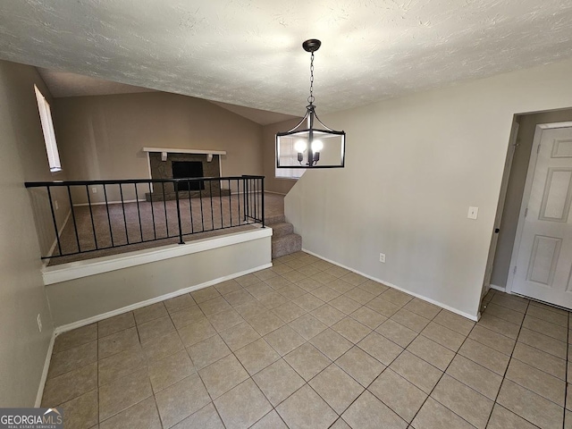 empty room with light tile patterned flooring, lofted ceiling, and a textured ceiling