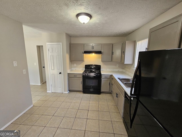 kitchen with gray cabinets, light tile patterned floors, a textured ceiling, and black appliances