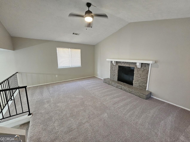 unfurnished living room featuring vaulted ceiling, a stone fireplace, carpet flooring, ceiling fan, and a textured ceiling