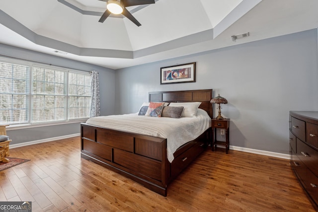 bedroom with hardwood / wood-style floors, a tray ceiling, and ceiling fan