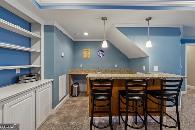 kitchen featuring pendant lighting, white cabinetry, a kitchen breakfast bar, and crown molding