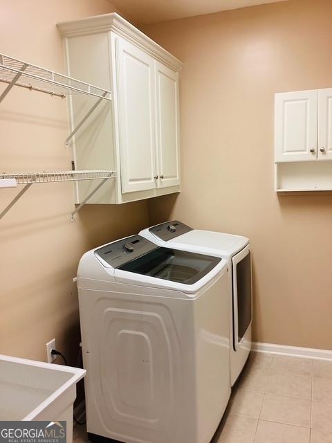 clothes washing area featuring cabinets, washing machine and dryer, sink, and light tile patterned floors