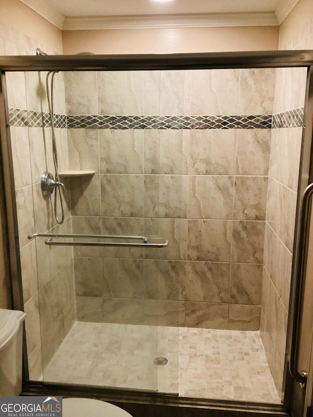 bathroom featuring a shower with shower door, ornamental molding, and toilet