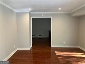 unfurnished room with ornamental molding and dark wood-type flooring